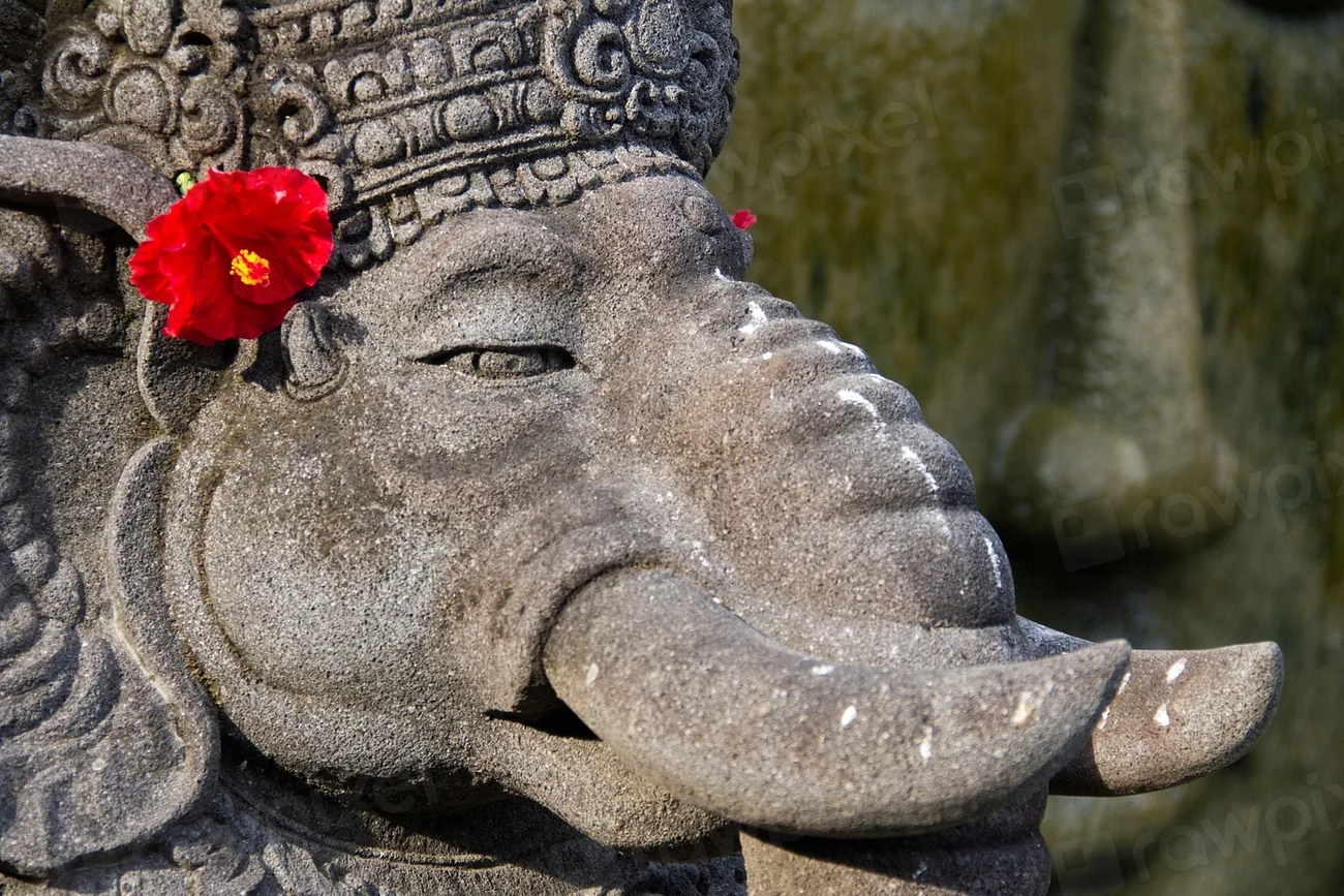 A carved stone guardian with a hibiscus flower