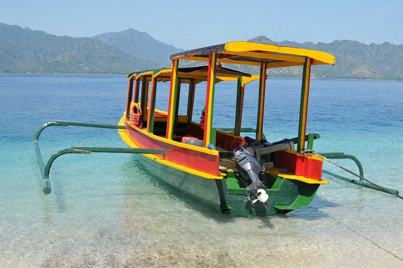 A traditional outrigger boat on clear shallow water
