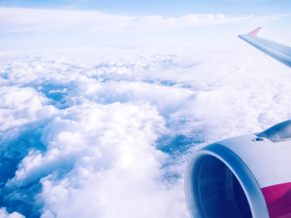 An aircraft engine and wing above thick cloud