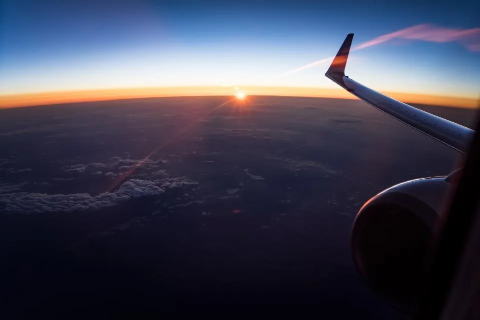 Sunrise seen from an aircraft window above the wing