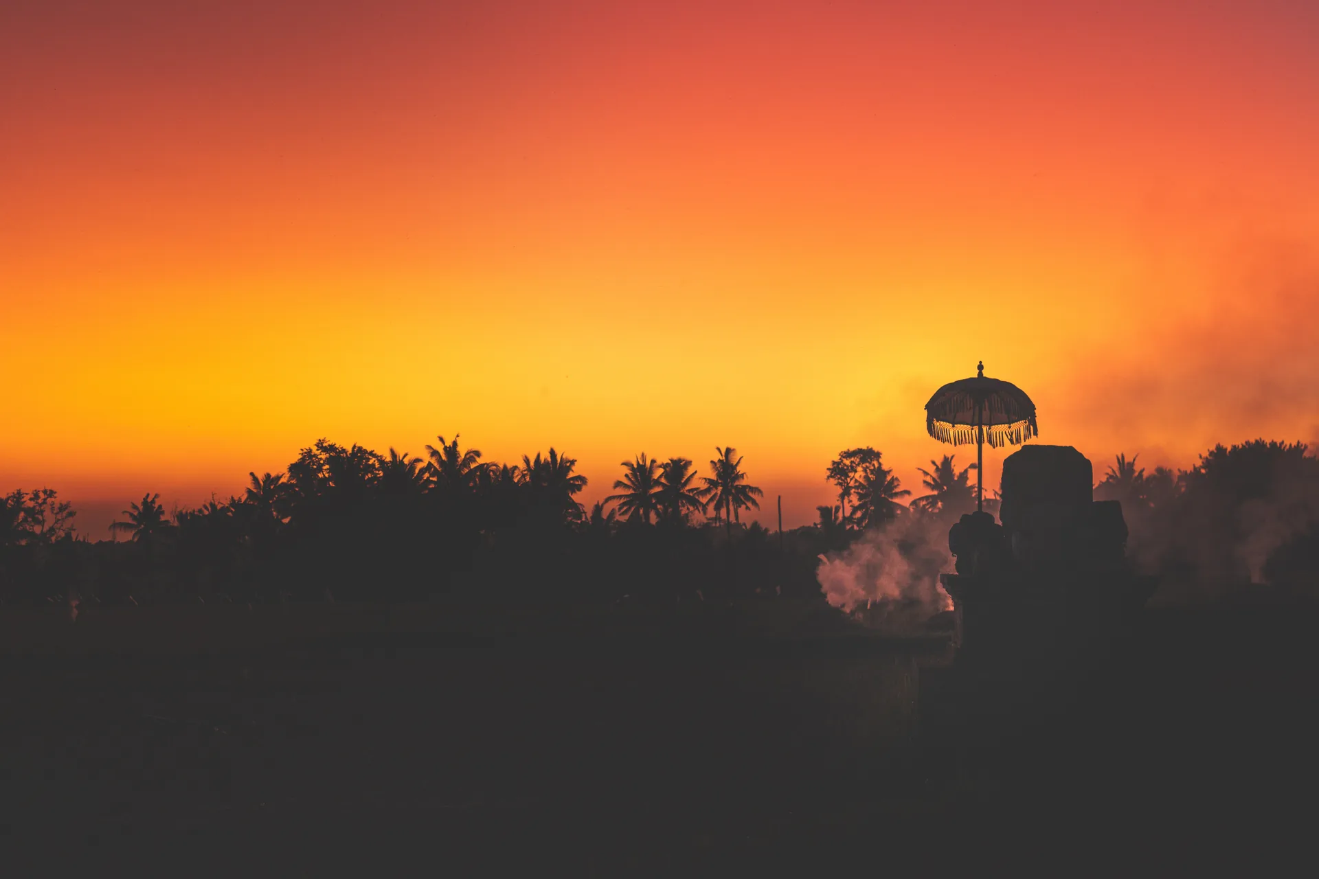 Sunset behind palms and a temple shrine